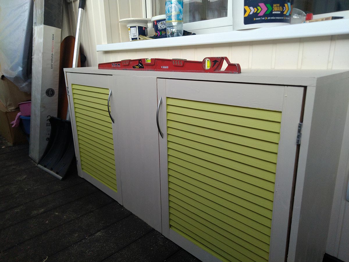 Небольшой, бело-зеленый деревянный шкафчик на лоджии